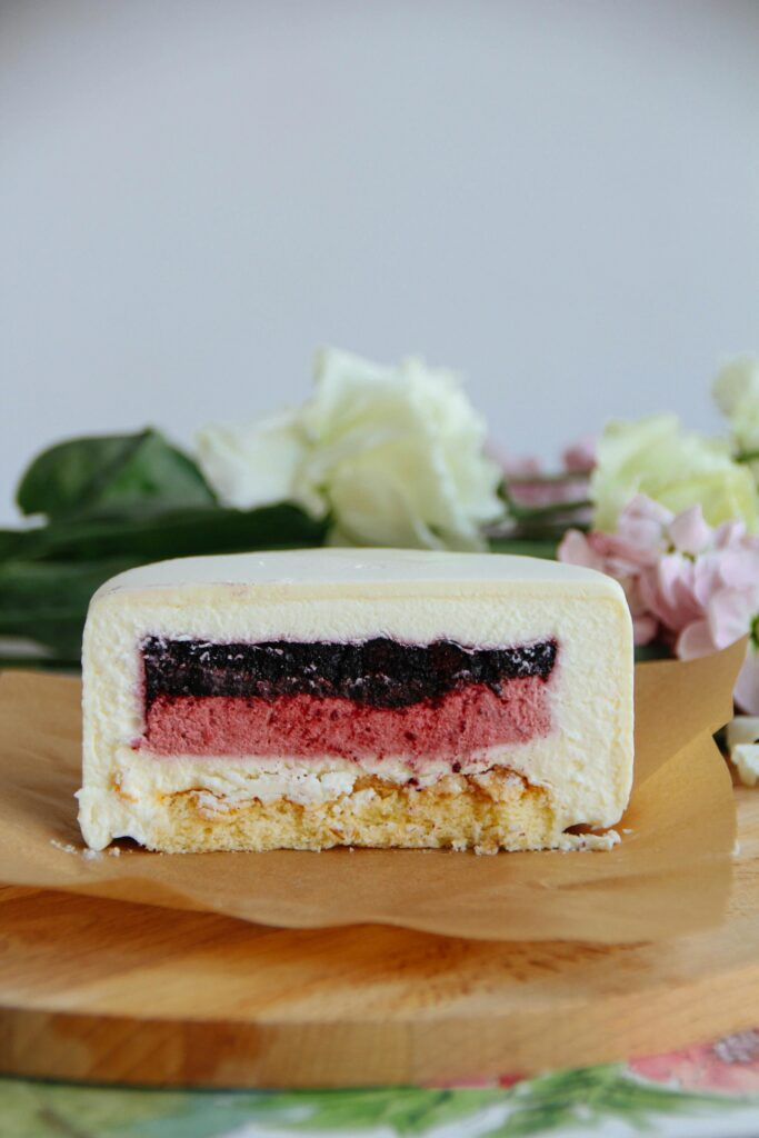 Appetizing layered cake with fruit filling on a wooden tray.